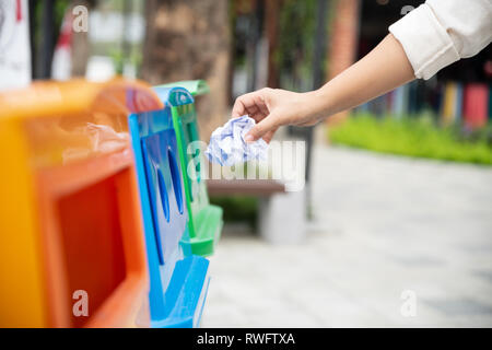 Ritratto closeup donna canto di gettare la carta stropicciata nel contenitore di riciclaggio. Foto Stock