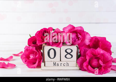 International Womens giorno concetto. Le rose rosa con il 8 marzo il testo sul blocco di legno del calendario sul bianco sullo sfondo di legno. Foto Stock