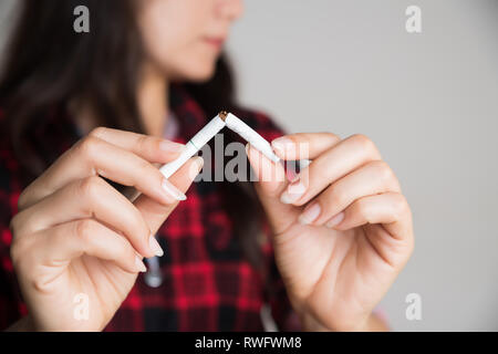 Celebra la Giornata Mondiale senza tabacco, 31 maggio. Smettere di fumare. Close up donna rottura a mano, schiacciamento o distruggendo le sigarette. Foto Stock