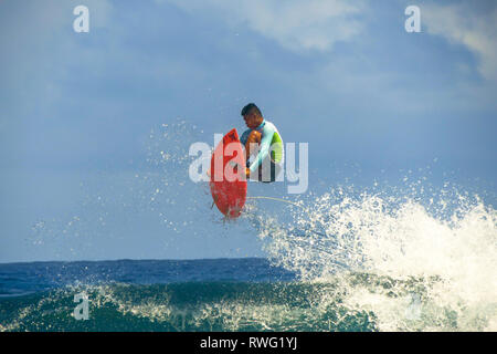 Surfer Jumping onda su piccolo rosso con la Tavola da Surf - Surf Cloud 9, Siargao - Filippine Foto Stock