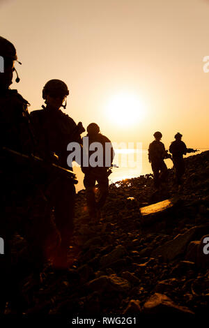 Silhouette di esercito di soldati con fucili contro un tramonto arancione. Foto Stock