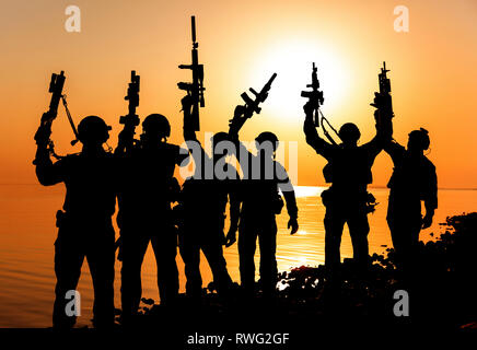 Silhouette di esercito di soldati con fucili contro un tramonto arancione. Foto Stock