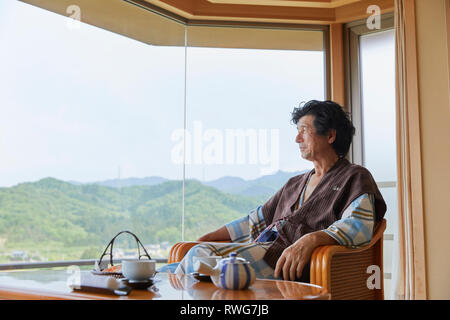 Senior giapponese uomo che indossa uno yukata presso un hotel tradizionale Foto Stock