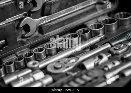 Piatto di metallo laici strumenti: chiavi, ratchet, un insieme di teste intercambiabili di dimensioni diverse e altri strumenti sono nella cassetta portautensili, una vista dall'alto. Close-up C Foto Stock