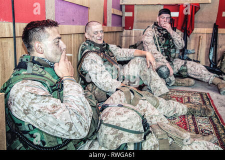 Stati Uniti Marines parlando e il riposo durante la seduta sul pavimento a loro avamposto di combattimento. Foto Stock