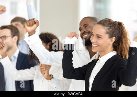Imprenditori e multirazziale i compagni di squadra per celebrare il successo del business in piedi in ufficio Foto Stock