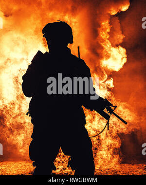 Silhouette di un moderno soldato di fanteria in piedi con il fucile di assalto su sfondo colorato. Foto Stock