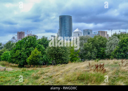 Scivolo di fango Park, London, Regno Unito - 18 agosto 2018: vista dal fango fattoria scivolo guardando verso Canary Wharf. con lungo erba selvatica e gli alberi in primo piano Foto Stock