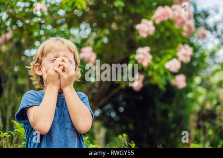 Ragazzo soffia il naso di fronte ad albero in fiore. Molla il concetto di allergia. I bambini di allergie Foto Stock