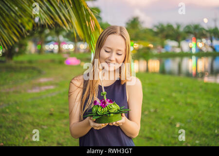 Giovane donna celebra Loy Krathong, corre sull'acqua. Loy Krathong festival, la gente compra i fiori e candela alla luce e galleggiare su acqua per celebrare Foto Stock