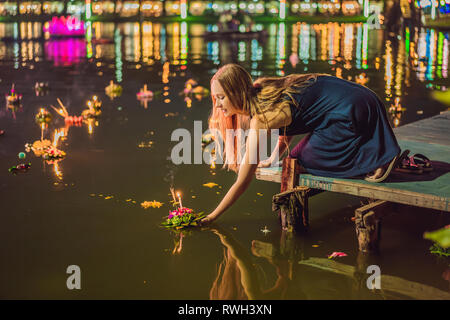 Giovane donna celebra Loy Krathong, corre sull'acqua. Loy Krathong festival, la gente compra i fiori e candela alla luce e galleggiare su acqua per celebrare Foto Stock