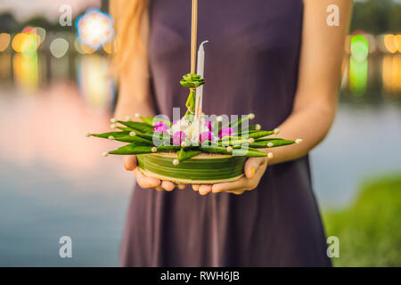 Giovane donna celebra Loy Krathong, corre sull'acqua. Loy Krathong festival, la gente compra i fiori e candela alla luce e galleggiare su acqua per celebrare Foto Stock