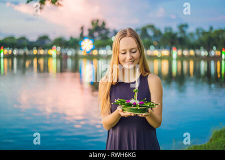 Giovane donna celebra Loy Krathong, corre sull'acqua. Loy Krathong festival, la gente compra i fiori e candela alla luce e galleggiare su acqua per celebrare Foto Stock