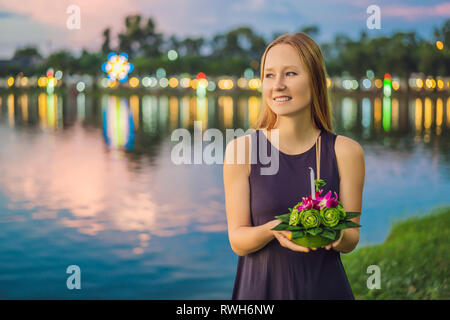 Giovane donna celebra Loy Krathong, corre sull'acqua. Loy Krathong festival, la gente compra i fiori e candela alla luce e galleggiare su acqua per celebrare Foto Stock