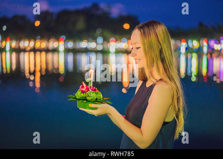 Giovane donna celebra Loy Krathong, corre sull'acqua. Loy Krathong festival, la gente compra i fiori e candela alla luce e galleggiare su acqua per celebrare Foto Stock