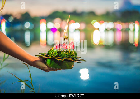 Giovane donna celebra Loy Krathong, corre sull'acqua. Loy Krathong festival, la gente compra i fiori e candela alla luce e galleggiare su acqua per celebrare Foto Stock