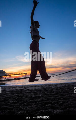 Regno Unito: meteo calde febbraio sul record nel Regno Unito a Ceredigion.Qui femmina, Donna,studente universitario su una linea di gioco,slackline, Aberystwyth,beach,Galles,UK, Foto Stock