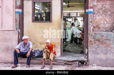 L'Avana, Cuba. Il 30 maggio 2009. Una coppia di anziani sedersi e rilassarsi su un passo al di fuori di un negozio di barbiere a l'Avana, Cuba. Foto Stock