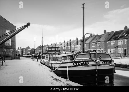 Vintage chiatte ormeggiate lungo la congelati beck (canale) e coperta di neve fiancheggiate da case in Beverley, Yorkshire, Regno Unito. Foto Stock