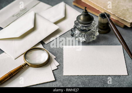 Set di vintage scrivendo articoli di cancelleria, penna in legno, inkwell, Magnifier e buste, lettere closeup. Foto Stock