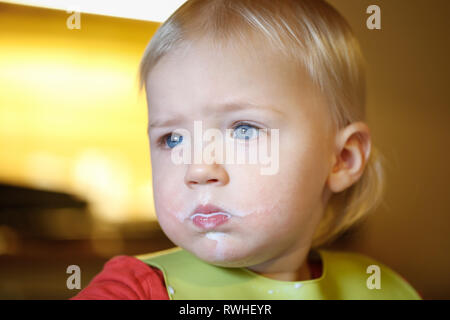 Bambino con latte di baffi da mangiare in modo indipendente, facendo un pasticcio. Lo sviluppo della prima infanzia, le tappe e i progressi, l'esperienza di apprendimento basate Foto Stock