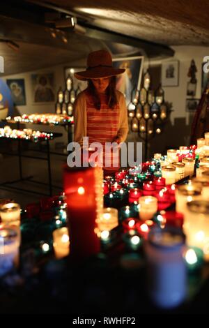 Bella ragazza giovane accende una candela nella cripta della chiesa di Saintes-Maries-de-la-Mer, la Camargue. Foto Stock