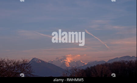 La montagna più alta in Europa diventa rosa al tramonto come le nuvole si raccolgono intorno al alta nevoso picco alpino. Foto Stock