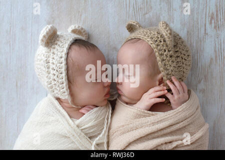 Profilo di headshot due, fraterno, twin, baby ragazze dormendo. Essi sono indossando maglia bear cappelli e sono swaddled in crema e marrone si avvolge. Foto Stock