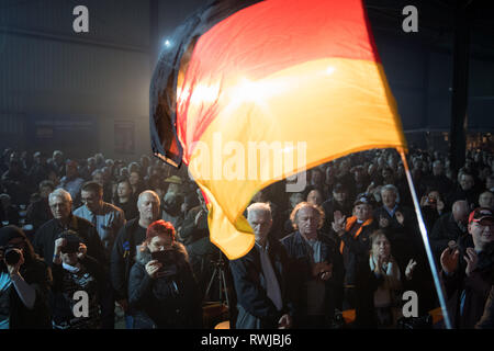 Bahretal, Germania. 06 Mar, 2019. I visitatori del Mercoledì delle Ceneri caso del partito Aufbruch deutscher Patrioten (ADP) stare dietro una bandiera tedesca. Credito: Sebastian Kahnert/dpa/Alamy Live News Foto Stock