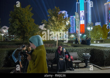 Grosny, Russia. 05 ott 2018. Residenti Grosnys sedersi la sera in un parco nel centro della citta'. Sullo sfondo i grattacieli di "Grozny City', su uno degli edifici si può vedere il ritratto di Ramzan Kadyrov, capo della Repubblica cecena. (A dpa storia 'Kadyrov la dittatura di Cecenia si trasforma in una bomba a orologeria") Credito: Emile Ducke/A4897/Emile Ducke/dpa/Alamy Live News Foto Stock