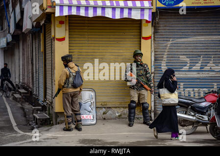 Srinagar Kashmir. Il 7 marzo 2019. Una donna vedere a piedi passato i paramilitari indiane uomini stavano in piedi in guardia durante l'arresto in Maisuma area di Srinagar.un arresto di sicurezza è di essere osservati nella zona Maisuma di Srinagar città. Jammu e Kashmir Liberation Front presidente Yasin Malik che è stato arrestato il 22 febbraio è stata prenotata a pubblico atto di sicurezza (PSA) e spostato a Kot Balwal carcere nel Jammu prima di oggi. Credito: Idrees Abbas SOPA/images/ZUMA filo/Alamy Live News Foto Stock