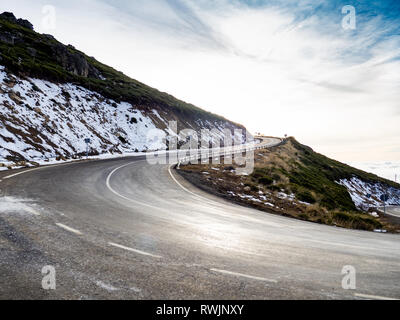 Molto curva chiusa su un pericoloso alta strada di montagna con cielo nuvoloso e neve su La Covatilla, Bejar (Salamanca) Foto Stock