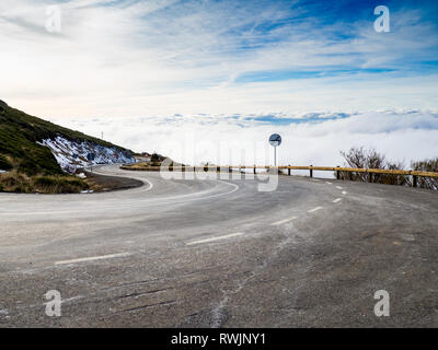 Molto curva chiusa su un pericoloso alta strada di montagna con cielo nuvoloso e neve su La Covatilla, Bejar (Salamanca) Foto Stock