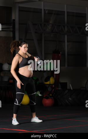 Femmine gravide di atleta facendo oscillare kettlebell allenamento Foto Stock