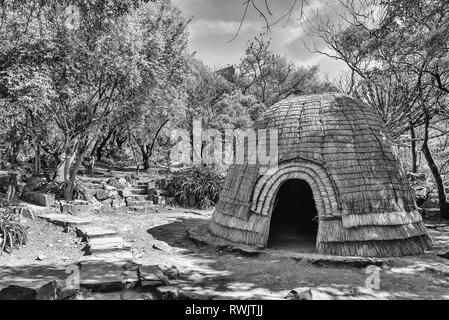 PRETORIA, SUD AFRICA, 31 luglio 2018: una replica capanna Zulu nella foresta al Monumento Voortrekker monumento sulla collina di Pretoria. Monocromatico Foto Stock