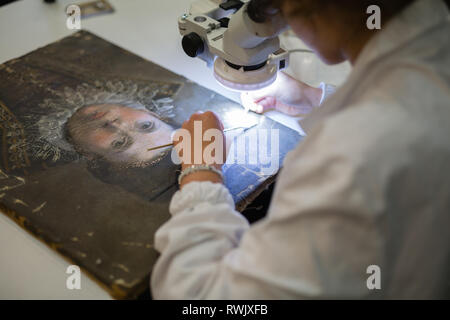 Un restauratore che sta lavorando sul restauro di un antico dipinto. Foto Stock