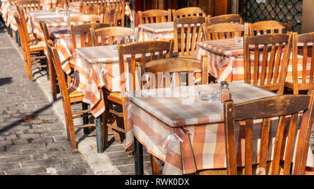 Il greco tipica taverna all'aperto, svuotare i tavoli e le sedie, giornata soleggiata, centro città Foto Stock