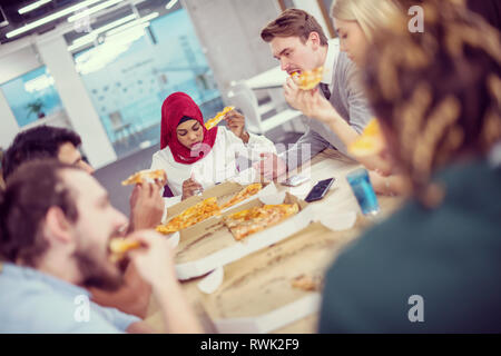 Amichevole multietnica diversi team aziendale la condivisione di mangiare la pizza insieme in ufficio di avvio, multirazziale i colleghi del gruppo del personale godendo di rompere parlando l Foto Stock
