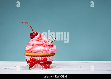 Tortina con crema di burro rosa ghiaccio e una ciliegina sulla torta. Foto Stock