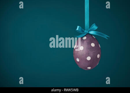 Tinti a mano viola polka-dot Uovo di Pasqua su sfondo teal Foto Stock