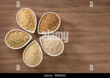 Un assortimento di grani interi di bocce su un sfondo di legno Foto Stock