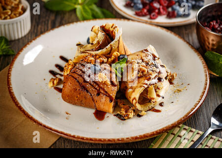 Crepes con crema di cioccolato decorate con noci e salsa al cioccolato Foto Stock