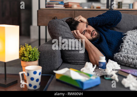 Piacevole uomo barbuto sdraiato sul divano Foto Stock