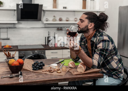 Piacevole giovane godendo il suo vino rosso Foto Stock