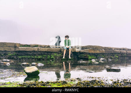 Ragazzo e cane godendo di mare Foto Stock