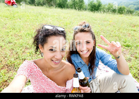 Gli amici sorseggiando picnic Foto Stock