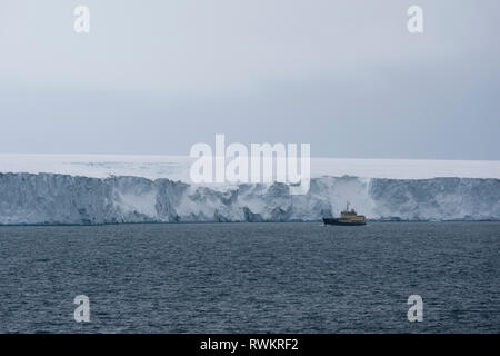 Nave passando le scogliere di ghiaccio della calotta glaciale polare, Austfonna Nordaustlandet, Svalbard, Norvegia Foto Stock