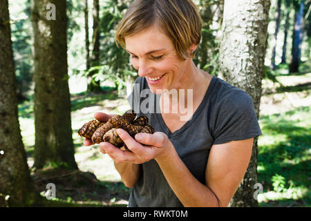 Donna con la manciata di pigne nella foresta, a Sonthofen, Baviera, Germania Foto Stock