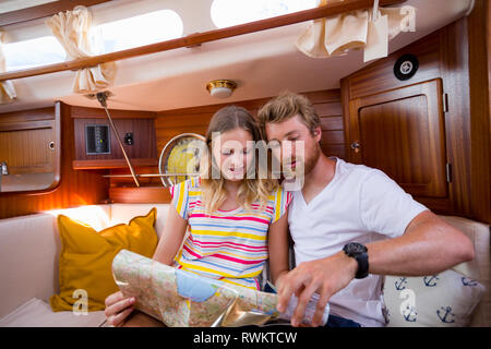 Coppia giovane in barca a vela cabin guardando la mappa di piegatura Foto Stock
