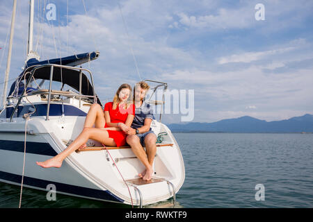 Coppia giovane seduto sulla barca a vela sul lago Chiemsee, Baviera, Germania Foto Stock